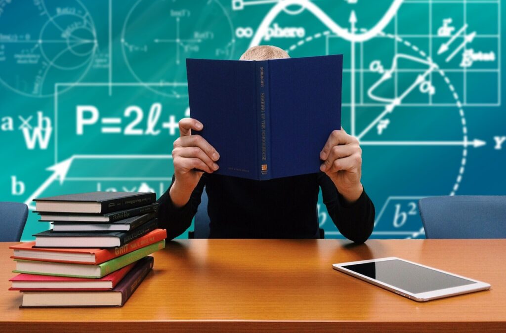 student learning new study skills at a desk with pile of books