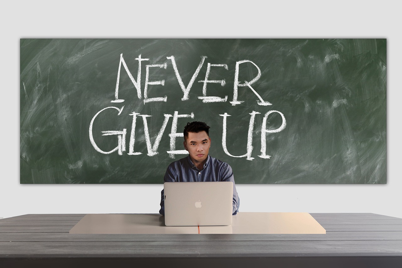 student sat in front of school board that says 'never give up'