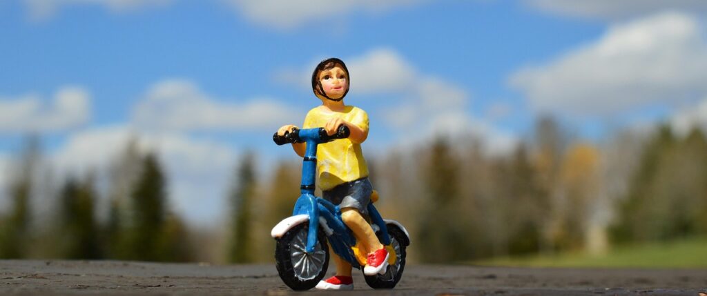Toy male figurine on bike outside